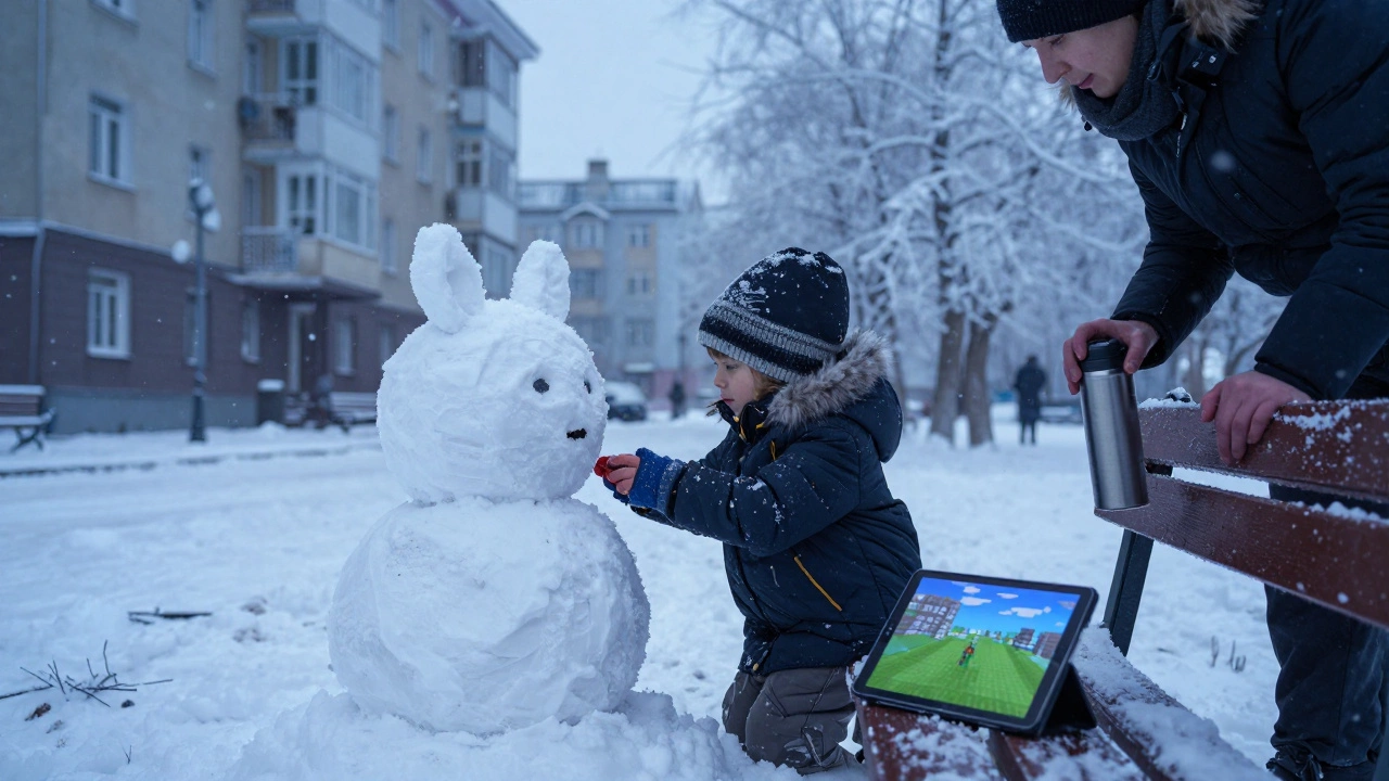 Ребёнок строит снежный замок зимой, планшет лежит выключенный рядом.
